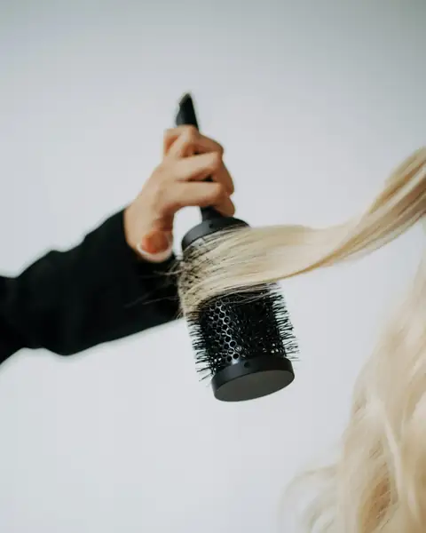 A round brush smoothing long blonde hair
